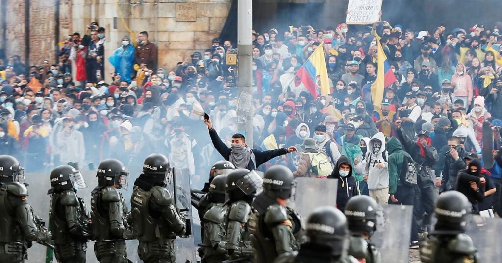 Colombian protesters advance through tear gas towards a police lline
