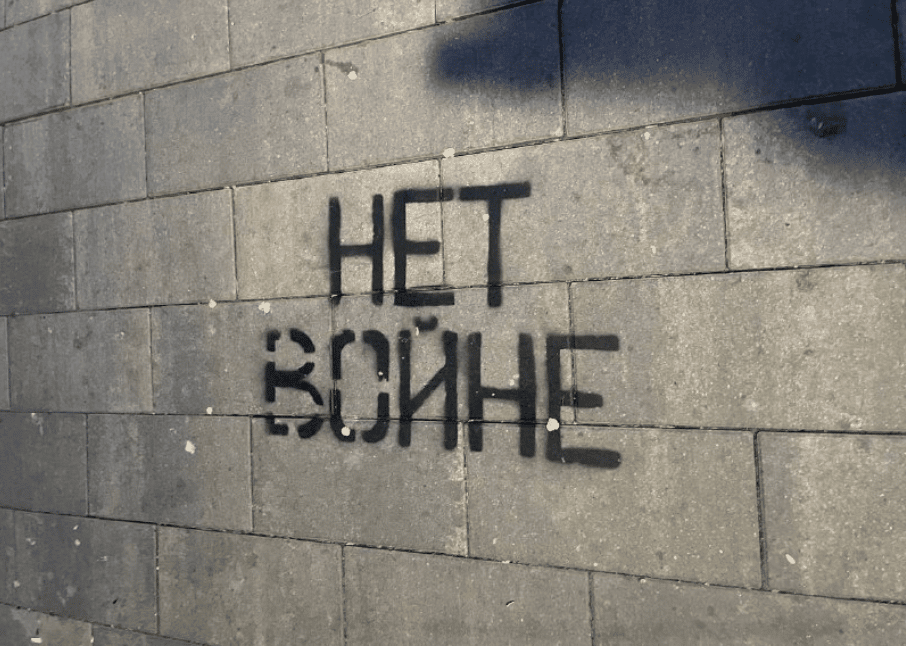 "No War" stencilled in black graffiti in Russian against a cinder block wall