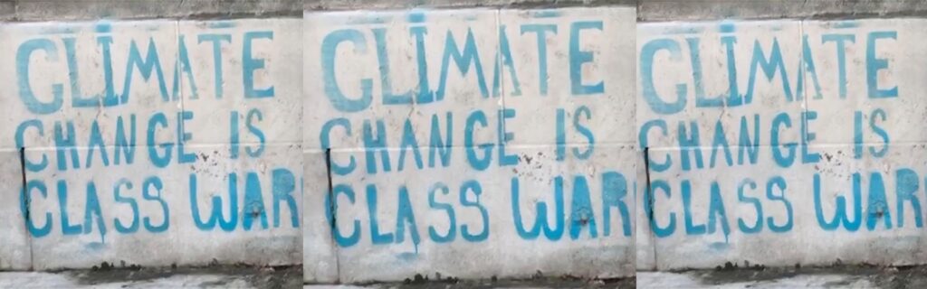 Climate Change Is Class War in clear three times in blue print on a white wall