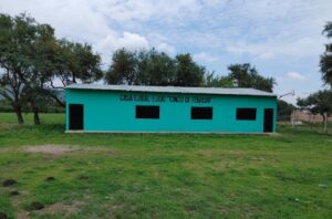 Green-blue Casa Ejidal in an agrarian setting in Comonfort, Mexico