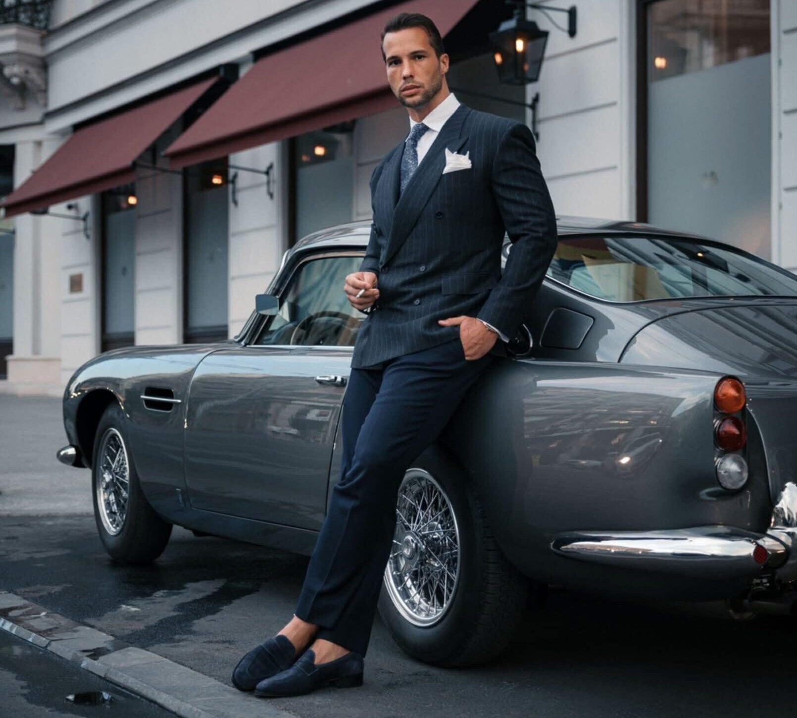 Tristan Tate standing next to an expensive car in an incongruous jacket, pant, and loafer combination. Tweet by Joseph D. McBride (@McBridgeLawNYC), X, July 23, 2025, 9:57 a. m.