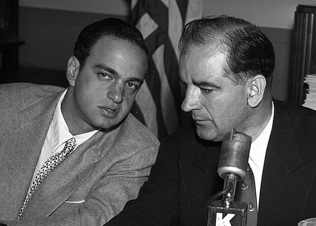 Sen. McCarthy, center, confers with Roy Cohn, chief counsel for House Un-American Activities Committee, during questioning of William Taylor. McCarthy indicated he may seek contempt citation against Taylor. At right is G. David Schine. Photo Credit: Los Angeles Times