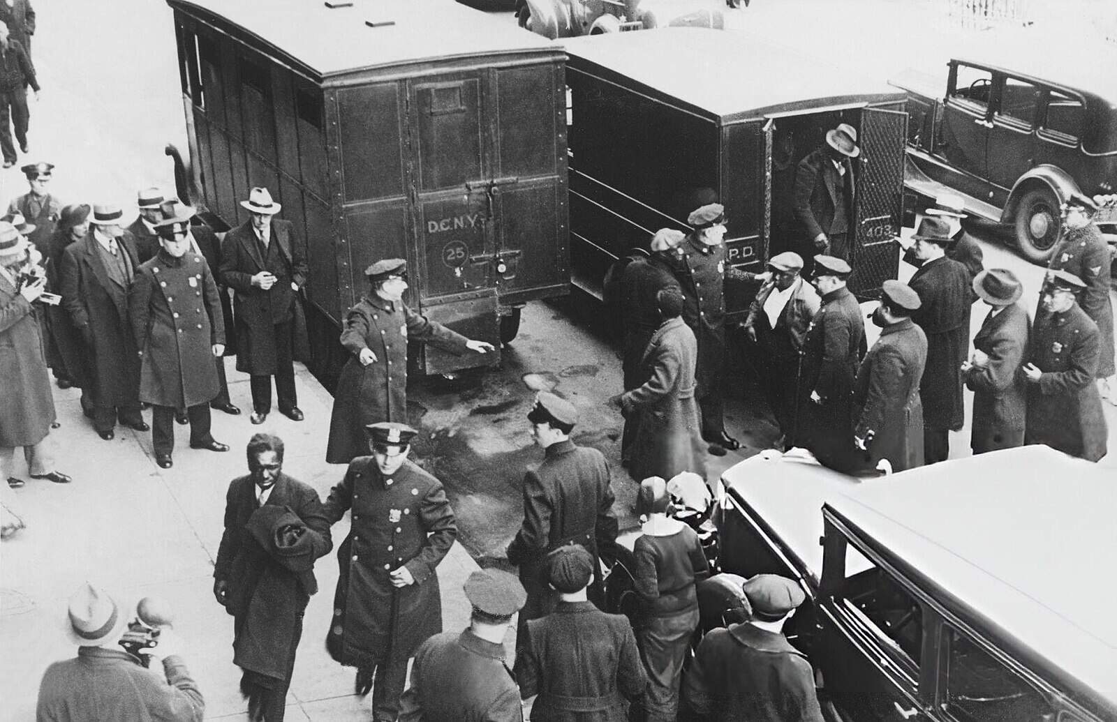 Police vans outside Harlem court on March 20, 1935, as prisoners arrested during the previous night’s riot were brought in for arraignment. Officers lead captives from the vans through crowds of onlookers. March 19, 1935 Photo Credit: AP Commons