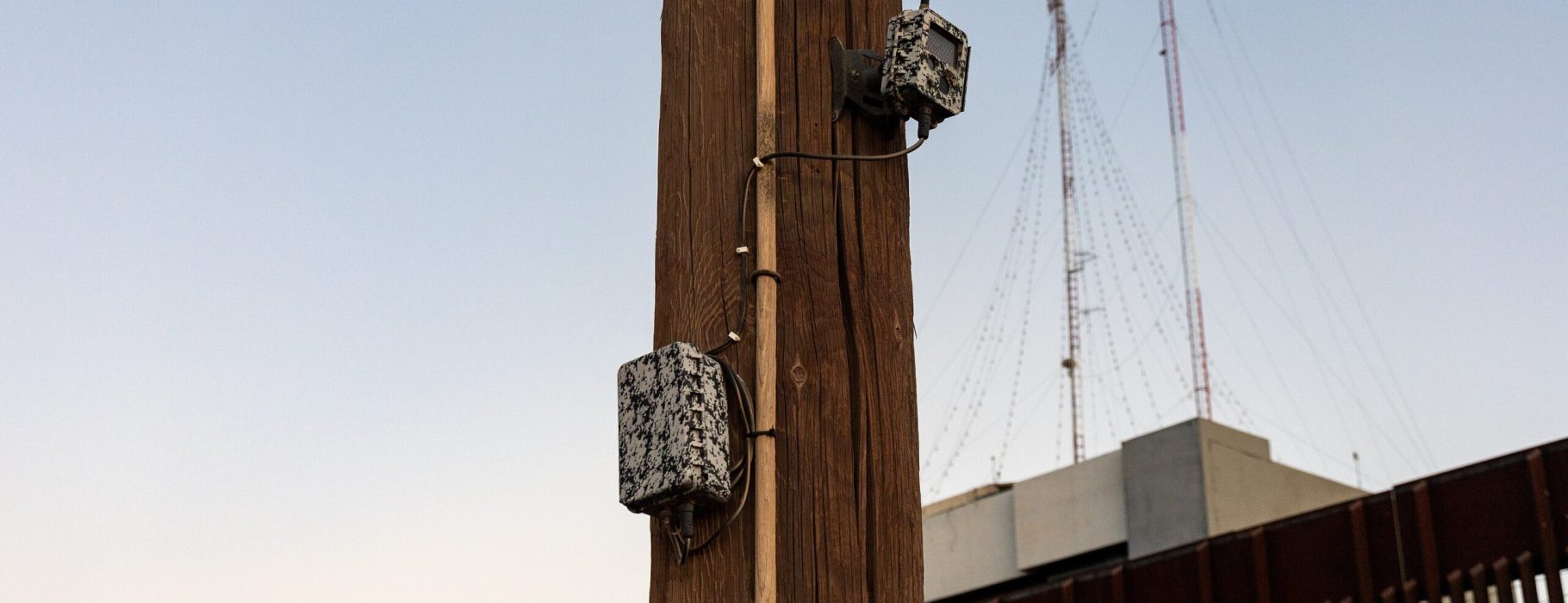 Remote camera on a pole with landing mat- and bollard-style border fencing in the background at the US/Mexico border in Calexico, California. Photo Credit: Dugan Meyer