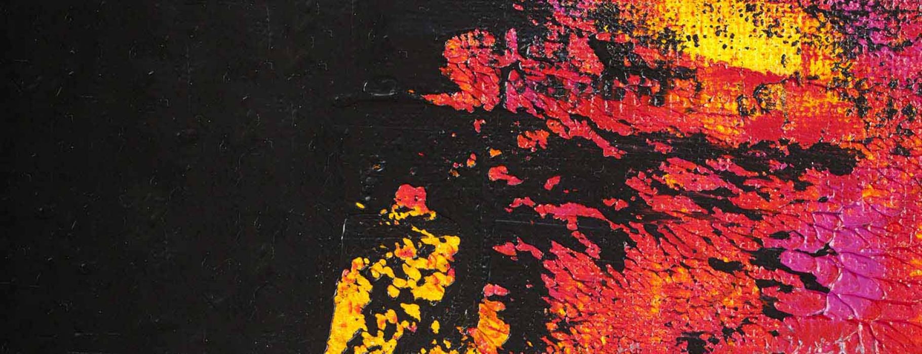 Abstract red, yellow, and ,magenta paint splotches applied to black canvas